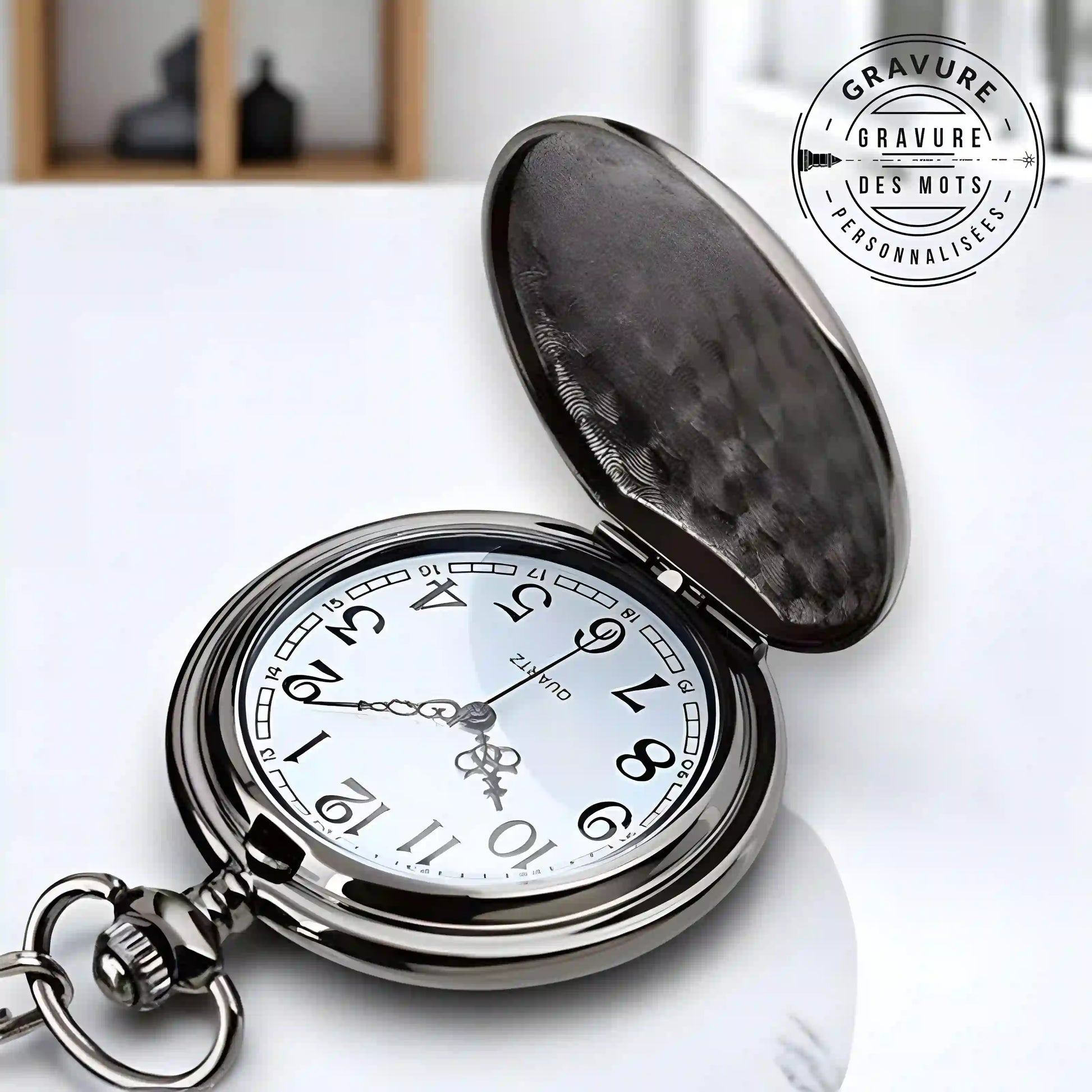 Montre gousset noire avec gravure , cadran blanc avec aiguilles et chiffre noirs