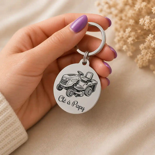 porte clé tracteur tondeuse en acier inox de couleur argent tenue dans une main de femme